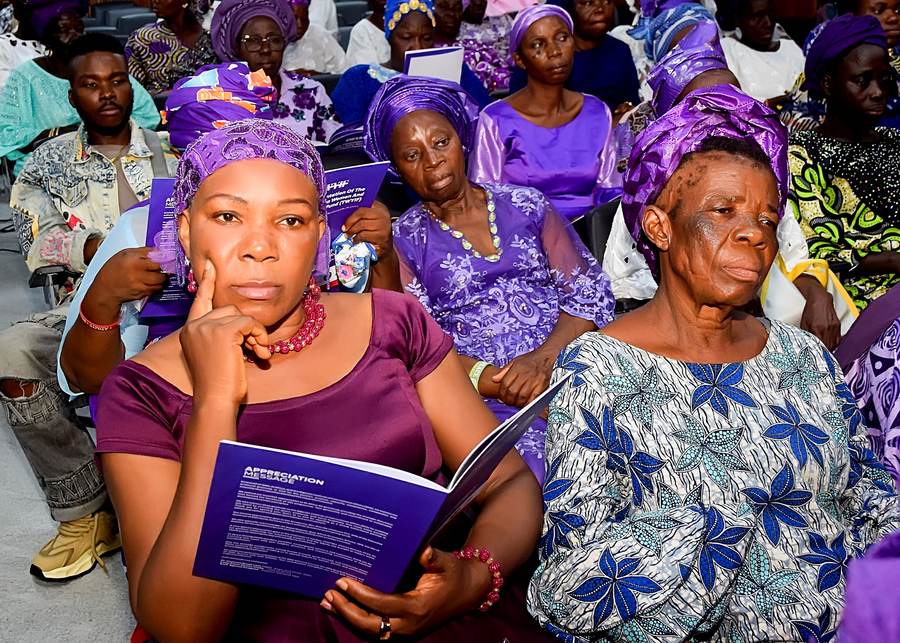 Women reading the programme at the public presentation of the Women and Youth Impact Fund.